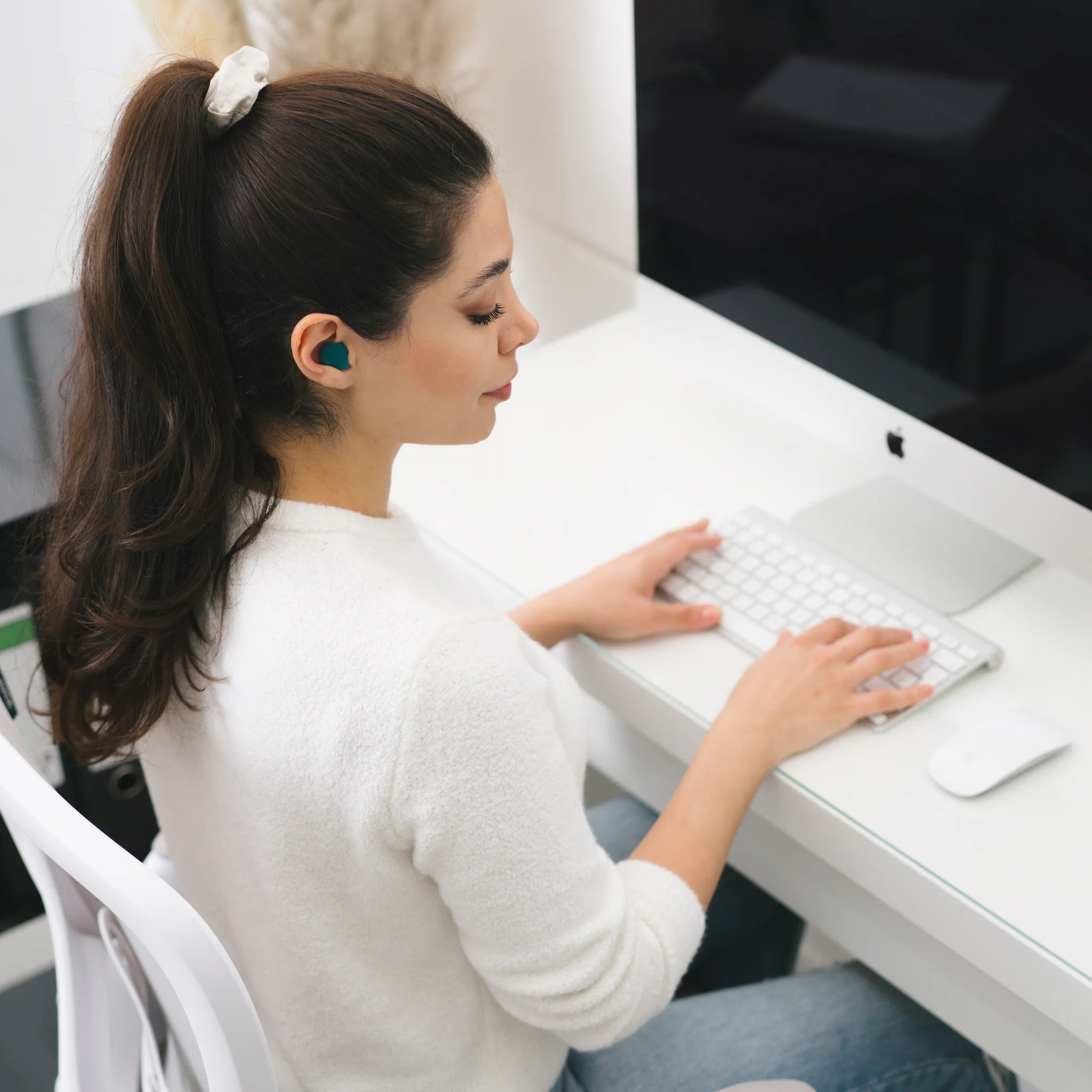 Vrouw werkt aan een bureau met siliconen oordoppen tegen snurken in haar oren.